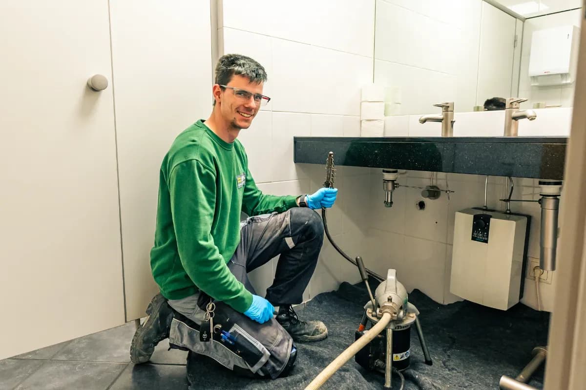 Techniker reinigt einen verstopften Küchenabfluss beim Kunden